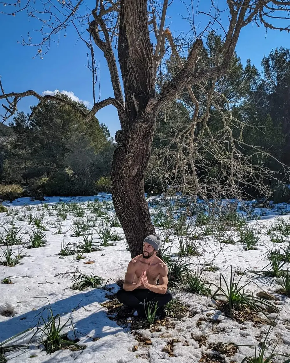 Miguel meditando con el torso desnudo sobre la nieve, bajo un almendro de la Serra de Tramuntana